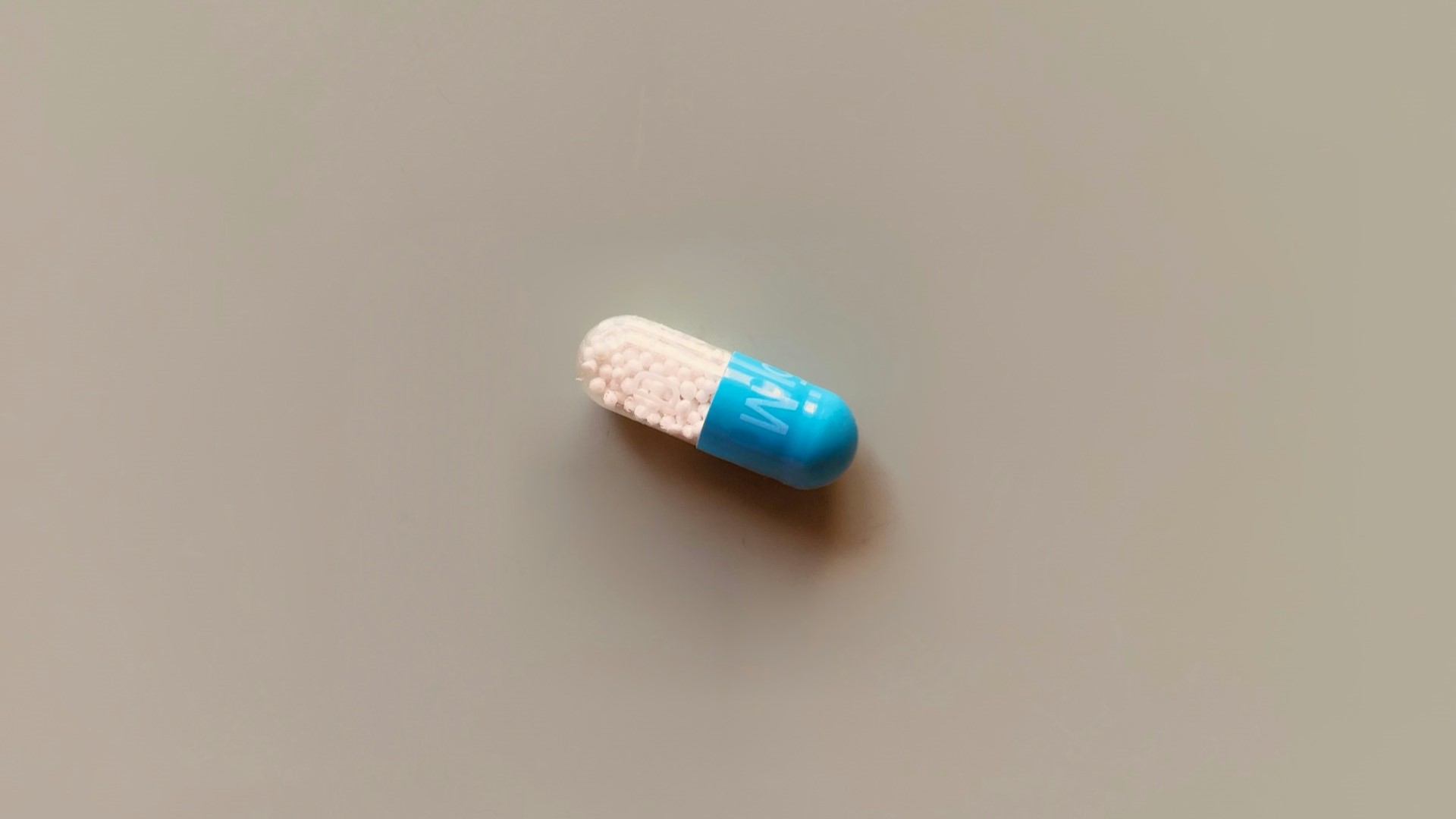 Blauw-witte capsule gevuld met witte microkorrels, vaak gebruikt bij microdoseren